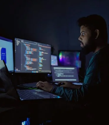 Engineer reviewing systems on multiple monitors