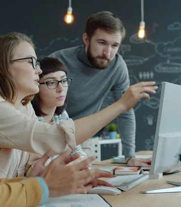 Team of colleagues collaborating around a computer in the office