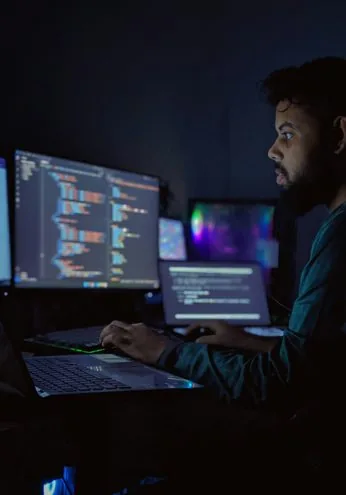 Telecom engineer reviewing network systems on multiple monitors